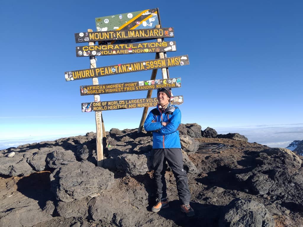 Solo Climber Standing At Uhuru Peak Kilimanjaro Summit Sign